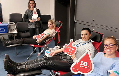 Vier Mitarbeiter in CEE Region auf Stühlen bei CSR-Aktivitäten (Foto)