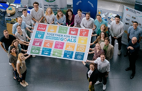 Eine Gruppe von rund 20 Personen hält ein Plakat mit SDG-Zielen.